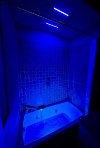 弗利OliVia Rooms Sauna & Gym的深色浴室设有蓝色灯光浴缸