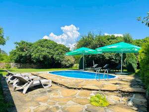 希萨里亚Къща за гости Вила Смокиня град Хисаря的一个带两把遮阳伞和两把椅子的游泳池和一个游泳池