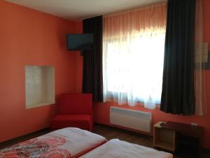 希萨里亚Къща за гости Вила Смокиня град Хисаря的一间卧室配有一张床、一张红色椅子和一个窗户
