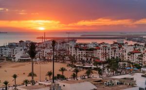 阿加迪尔ALIYA LUXURY APARTMENT El HOUDA-AGADIR的海滩和建筑的城市日落