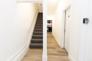 奥尔德姆Suite 1 - Lovely Ensuite in Oldham Sociable House的走廊设有楼梯,走廊设有白色墙壁