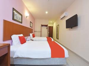 马六甲MRC Hotel Melaka Raya的卧室配有一张床,墙上配有电视。