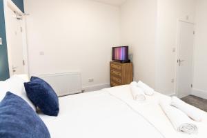 奥尔德姆Suite 1 - Lovely Ensuite in Oldham Sociable House的一间卧室配有一张带蓝色枕头的白色床和电视。