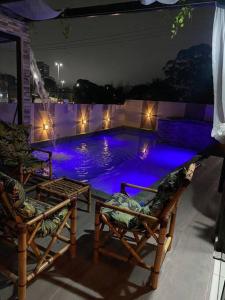 莫日-达斯克鲁济斯Alugo espaço com piscina + Jacuzzi!的游泳池晚上配有两把椅子和灯