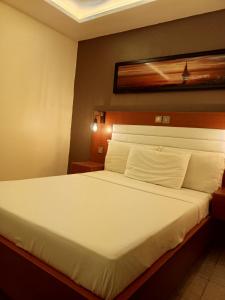 林贝First International Inn Downtown的一间卧室配有一张带白色床单的大床