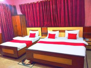 卡拉奇Jinnah Airport Hotel的配有红色窗帘的客房内的两张床