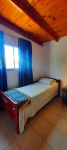 吉亚迪诺镇Casa V.Giardino pileta y cochera的一间卧室配有一张带蓝色窗帘的床和一扇窗户
