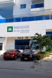 卡塔赫纳apartaestudio independiente en Manga, Cartagena的两辆汽车停在大楼前的停车场