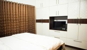 德里久尔Urban Oasis Homestay: AC Bedrooms的一间卧室配有一张床、一台电视和橱柜