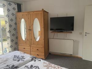 奥尔斯贝格瓦德索赫度假公寓的一间带电视和带两面镜子的木柜的卧室