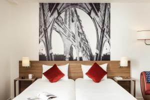 库尔布瓦拉德芳斯库尔布瓦阿德吉奥公寓式酒店的一间卧室配有一张带红色枕头的大床