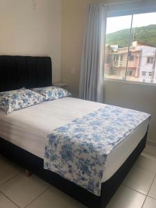 弗洛里亚诺波利斯Comodidade e simplicidades a 240m do mar的一间卧室配有一张带蓝白色毯子的床