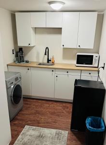 TrailComfy Home的厨房配有白色橱柜、水槽和微波炉