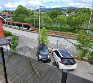 卑尔根Nesttunveien appartments的两辆汽车停在火车旁边的停车场