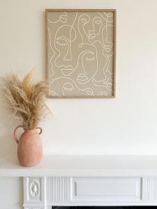 莱斯特FOSSE LUXURY ROOMS的墙上一幅画作的架子上的花瓶