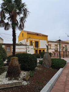 托莱多Casa de Vivar a 5 minutos de Puy du Fou的一座黄色和白色的建筑,前面有棕榈树