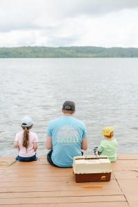 甘特斯维尔Deluxe Glamping Tents at Lake Guntersville State Park的坐在码头上的男人和两个孩子