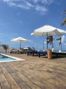 特赖里Villa Casa Ava Kite - Guajiru的一组桌子,在泳池旁摆放着遮阳伞