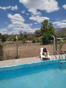 圣奥古斯汀镇Complejo de Cabañas Las Mellizas的坐在游泳池旁椅子上的女人