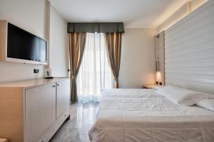 利尼亚诺萨比亚多罗哥伦布酒店的一间卧室配有一张床和一台平面电视