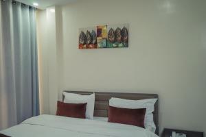 努瓦克肖特Urban Hotel Nouakchott的一间卧室配有带白色床单和红色枕头的床。