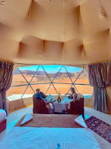 瓦迪拉姆Wadi Rum Relaxation Camp的两人坐在带大窗户的房间里椅子上