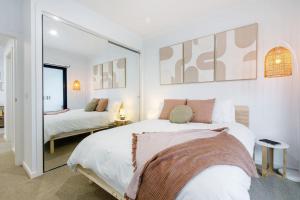 墨尔本'Laidback Lygon' A Two-storey Inner-city Oasis的一间白色卧室,配有两张床和镜子