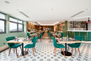 岘港Hadana Boutique Hotel的一间带桌子和绿色椅子的餐厅