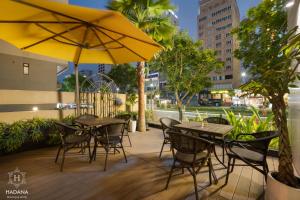 岘港Hadana Boutique Hotel的一个带桌椅和遮阳伞的庭院