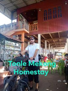 Krong KrachehTonle Mekong Homestay的骑摩托车的人在房子前骑摩托车