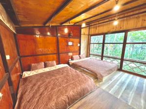 Làng CacDu Gìa - Mường Trà Garden Homestay的配有木墙和窗户的客房内的两张床