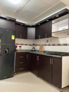 圣玛尔塔La Casa de Ian的厨房配有棕色橱柜和黑色冰箱
