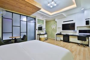 蔚山G&G Hotel的一间卧室配有一张床、一张书桌和一台电视。