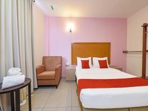 马六甲MRC Hotel Melaka Raya的配有一张床和一把椅子的酒店客房
