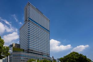 名古屋The Royal Park Hotel Iconic Nagoya的蓝色天空的高玻璃建筑