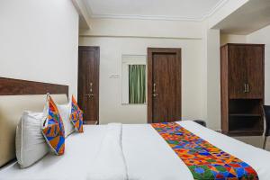 浦那FabHotel Irish Koregaon Park的卧室配有一张带彩色枕头的大型白色床。