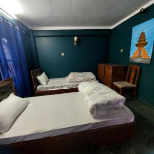 巴克塔普尔Luniva Restaurant And Guest House的蓝色墙壁客房的两张床