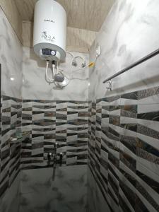 瓦拉纳西Kashi Vandanam Homestay的浴室的墙壁上设有瓷砖和淋浴。