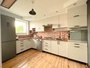 格但斯克Apartament Plaża 50的厨房铺有木地板,配有白色橱柜。