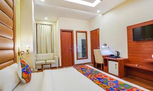 诺伊达FabHotel Prime Noida Sector 63的酒店客房配有一张床、一张书桌和一台电视。