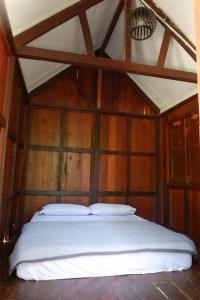 甘榜珍德拜Jungle Zen Janda Baik Campsite的木制客房内的一间卧室,配有一张床