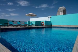 迪拜迪拜矽谷绿洲普瑞米尔酒店的一座大楼顶部的游泳池,配有椅子和遮阳伞