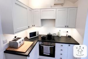 梅德斯通The Little House的厨房配有白色橱柜和台面上的微波炉