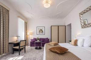 捷克克鲁姆洛夫Bellevue Hotel Český Krumlov的一间卧室配有一张大床和一张紫色沙发