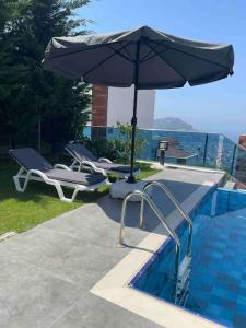 阿拉尼亚Villa, Alanya, Antalya的游泳池旁的遮阳伞和躺椅