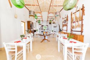莱切省卡瓦利诺Masseria Tenuta Le Menze的用餐室配有白色的桌子和白色的椅子