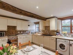 Swimbridge3 Bed in Barnstaple 60511的厨房配有白色橱柜和鲜花桌