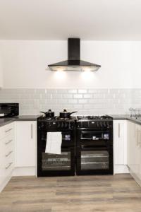 奥尔德姆Suite 2 - Comfy Spot in Oldham Sociable House的厨房配有黑炉和白色橱柜