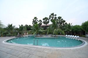 AnnavaramSpree One Resort And Convention Annavaram的一个带白色椅子和棕榈树的游泳池