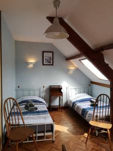 HenneveuxLe Gîte du Bois Groult的阁楼卧室配有两张床和钢琴